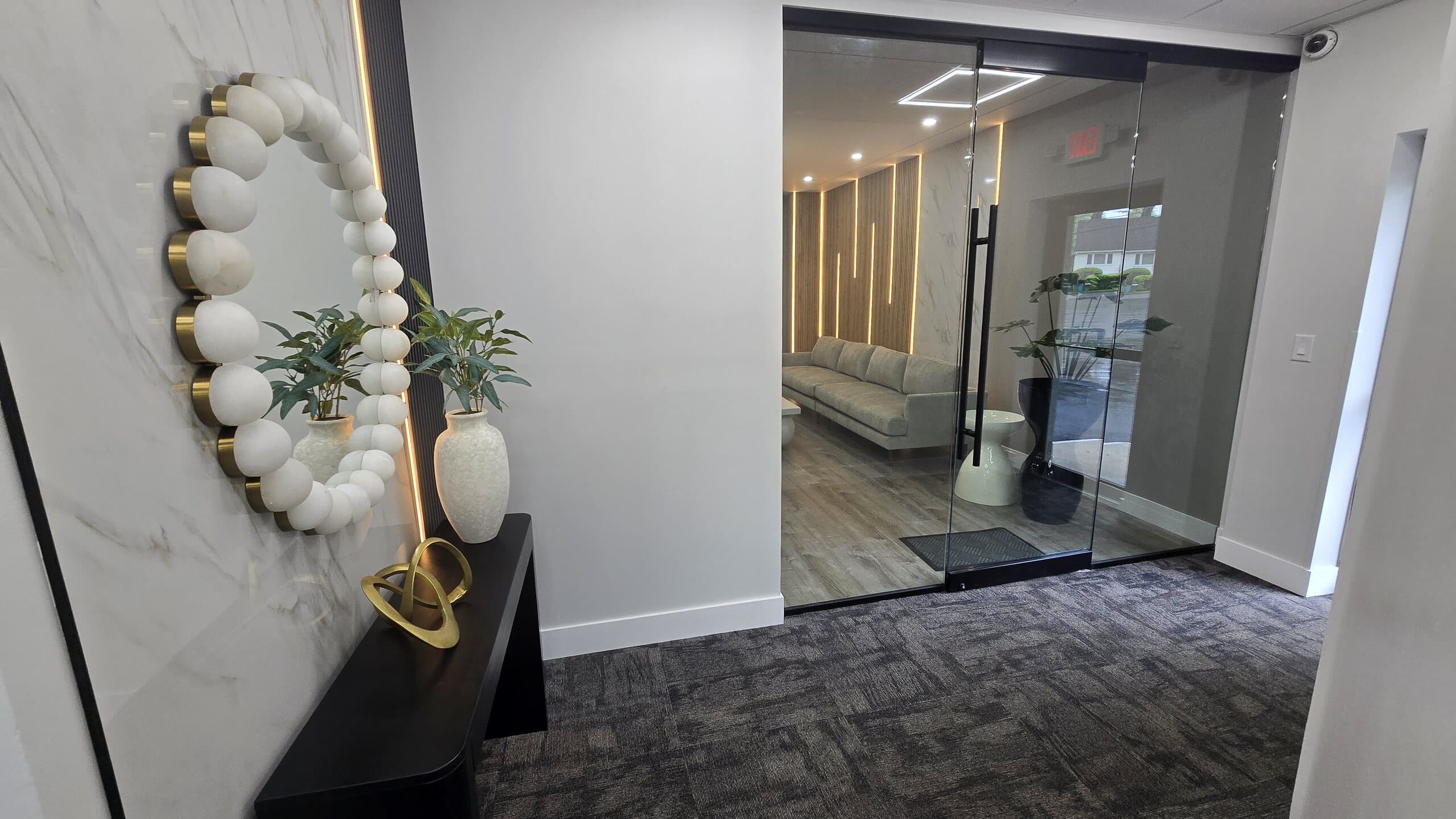 The entry at 360 Health Center, with a marble wall, sculptural gold mirror, and glass door into the waiting room.